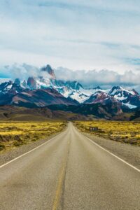 Argentina travel along a scenic road leading toward snowcapped mountains in Patagonia.