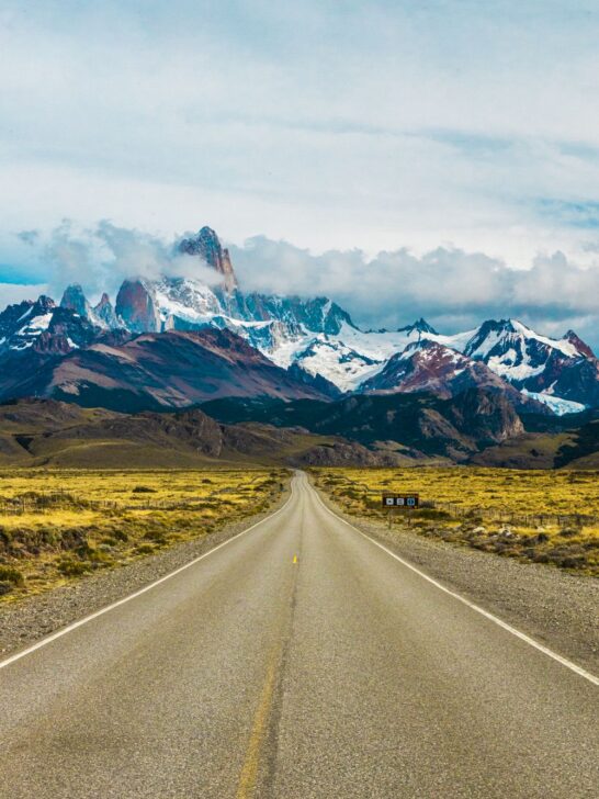 Argentina travel along a scenic road leading toward snowcapped mountains in Patagonia.