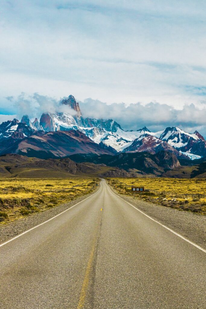 Argentina travel along a scenic road leading toward snowcapped mountains in Patagonia.
