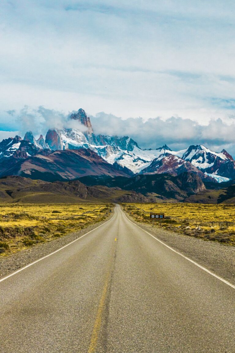 Argentina travel along a scenic road leading toward snowcapped mountains in Patagonia.