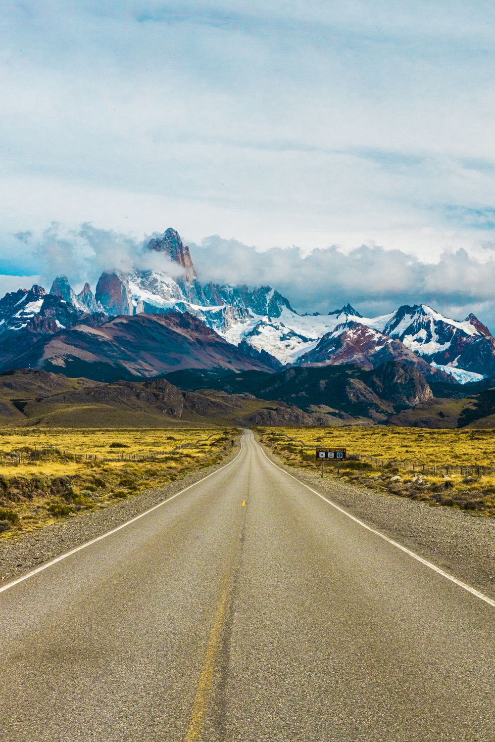 Argentina travel along a scenic road leading toward snowcapped mountains in Patagonia.