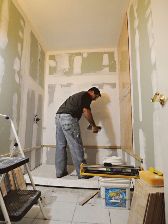 Contractor installing tile during a bathroom remodel planning and renovation project.