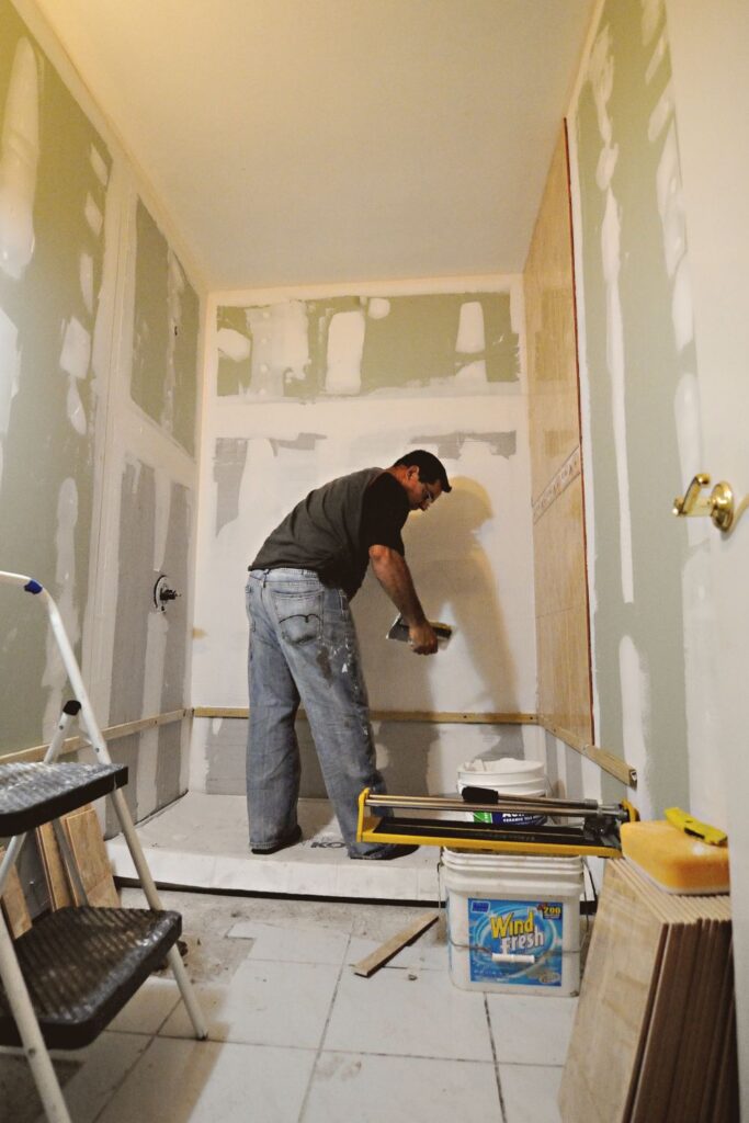 Contractor installing tile during a bathroom remodel planning and renovation project.