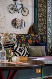 Modern interior with botanical wallpaper, vintage wood doors, patterned flooring, and a red accent chair