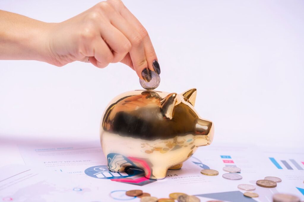 Person adding a coin to a piggy bank while setting aside savings for unexpected property repairs.