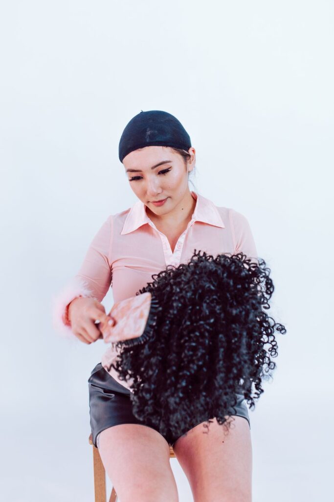 Woman brushing a curly black wig before styling