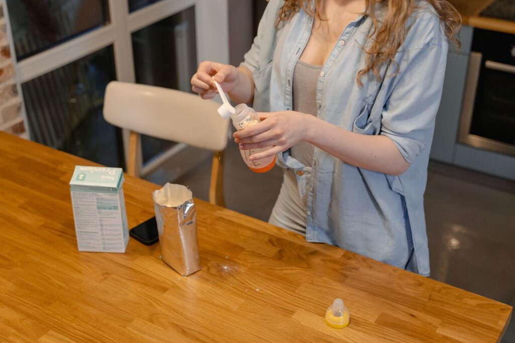 Woman preparing a bottle of baby formula at a kitchen table