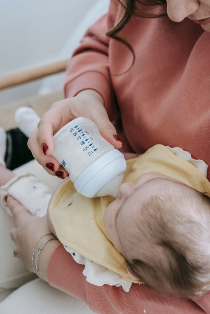 A mothre bottle feeding a baby while holding them in her arms