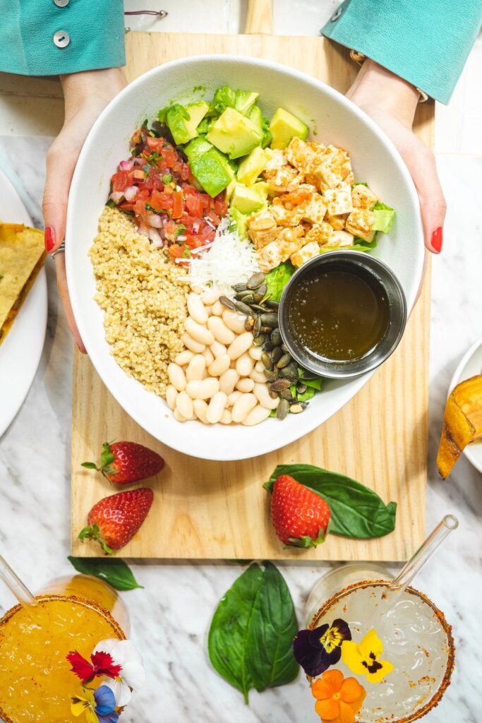 Healthy lunch ideas with quinoa, chicken, white beans, avocado, vegetables, and seeds in a bowl