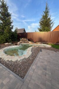 Clear backyard garden pond with stone edging, waterfall, and surrounding landscaping Do you like this personality?