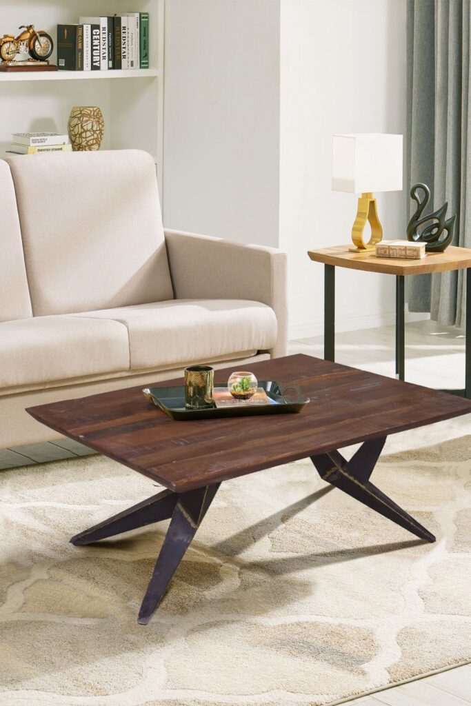 Stylish wooden coffee table with metal legs positioned in front of a neutral sofa in a modern living room.