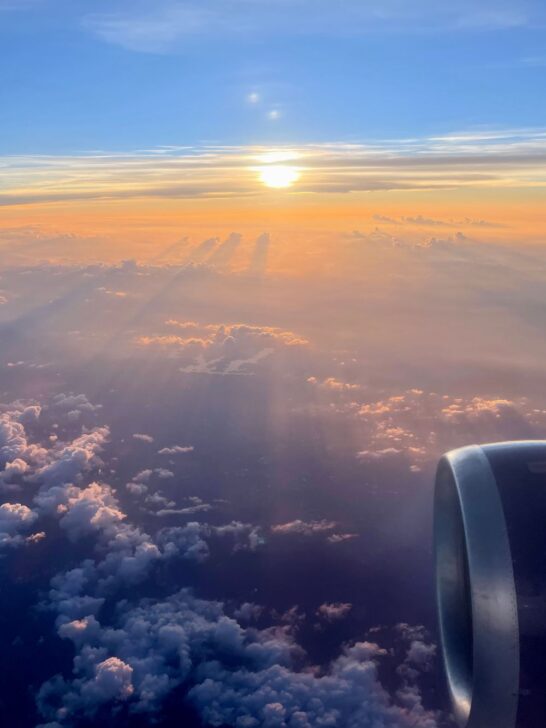 Airplane flying above the clouds at sunset during a luxury getaway
