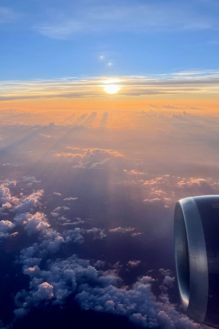 Airplane flying above the clouds at sunset during a luxury getaway