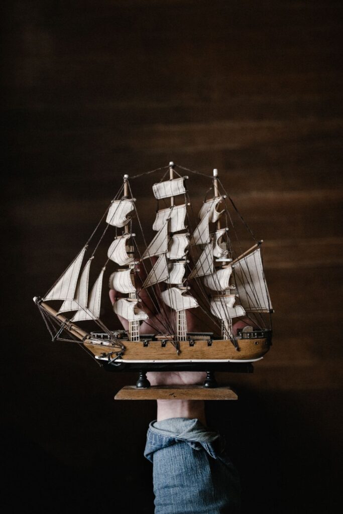 Hand holding a detailed wooden sailing ship for model ship building