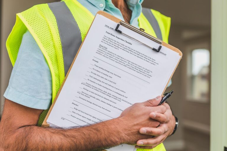 Home inspector holding a clipboard and pen while reviewing a renovation safety checklist.