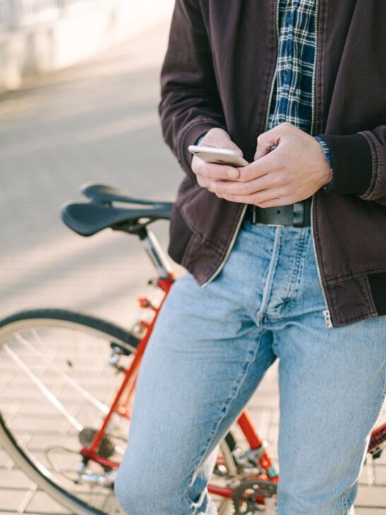 Person using a smartphone while standing beside a bicycle