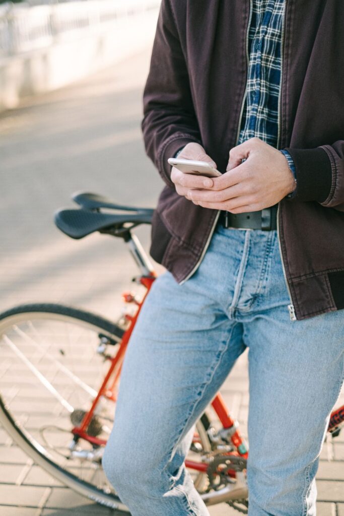 Person using a smartphone while standing beside a bicycle