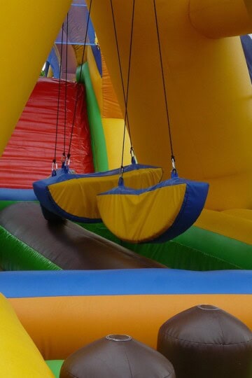 Colorful course with hanging obstacles and a climbing ramp, an example for parents buying an inflatable obstacle course.