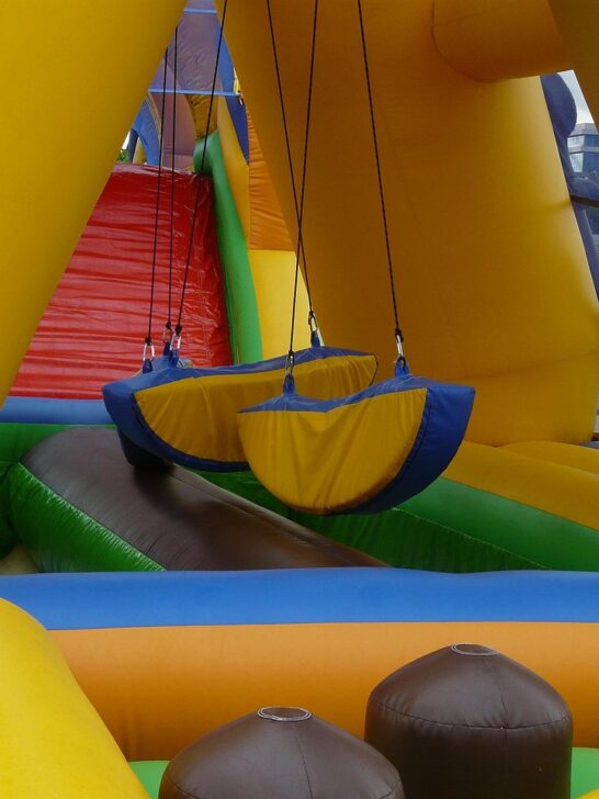 Colorful course with hanging obstacles and a climbing ramp, an example for parents buying an inflatable obstacle course.