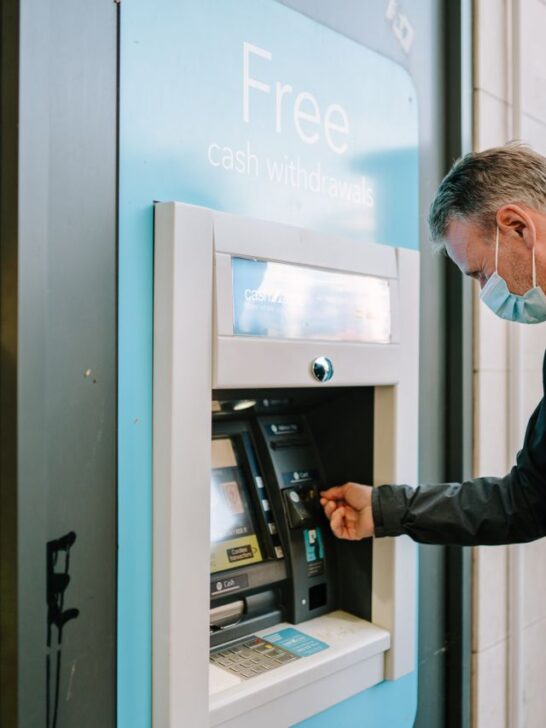 Man using an ATM with a sign advertising free cash withdrawals.