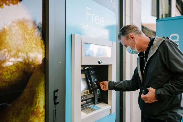 Man using an ATM with a sign advertising free cash withdrawals.