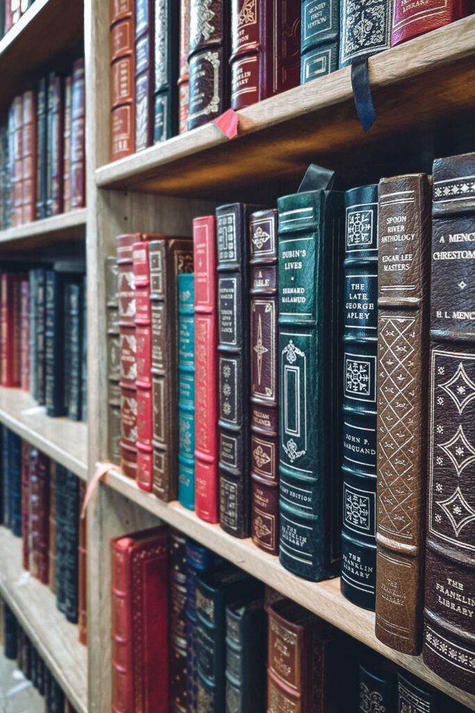 Leather-bound literature books with decorative spines on wooden shelves, illustrating resources for developing critical reading skills.