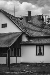 Home exterior damage showing missing and displaced roof tiles on an older house.