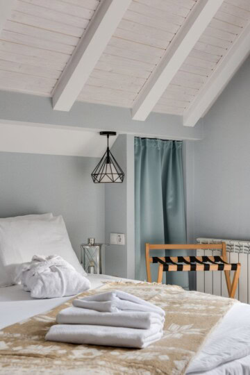 Hotel-inspired guest room ideas featuring white bedding, neatly folded towels, and a wooden luggage rack.
