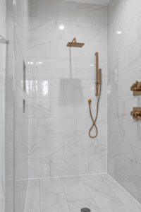 Modern marble bathroom with gold shower fixtures illustrating how to choose a shower water filter for your home.