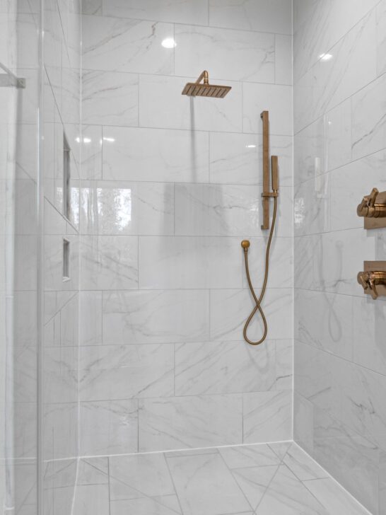 Modern marble bathroom with gold shower fixtures illustrating how to choose a shower water filter for your home.
