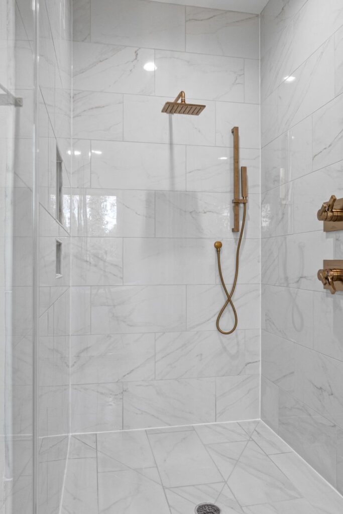 Modern marble bathroom with gold shower fixtures illustrating how to choose a shower water filter for your home.