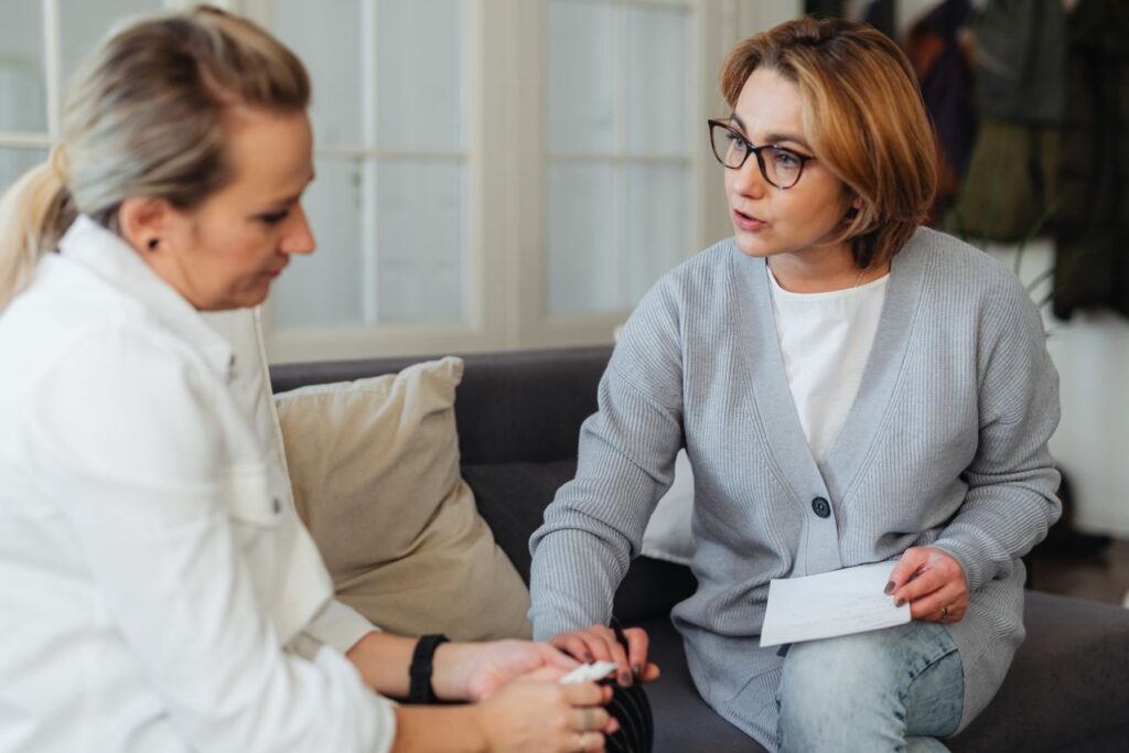 Woman discussing individual health needs with a healthcare professional while holding paperwork.