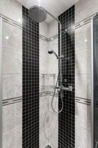 Shower remodel tips featuring black and cream tile, a rainfall showerhead, handheld sprayer, and corner storage baskets.