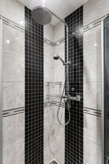 Shower remodel tips featuring black and cream tile, a rainfall showerhead, handheld sprayer, and corner storage baskets.