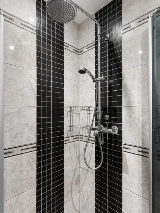 Shower remodel tips featuring black and cream tile, a rainfall showerhead, handheld sprayer, and corner storage baskets.