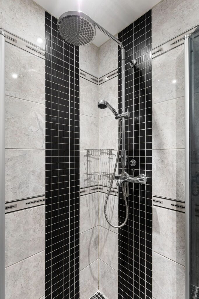 Shower remodel tips featuring black and cream tile, a rainfall showerhead, handheld sprayer, and corner storage baskets.