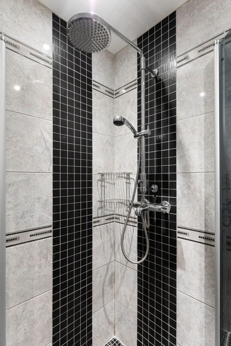 Shower remodel tips featuring black and cream tile, a rainfall showerhead, handheld sprayer, and corner storage baskets.