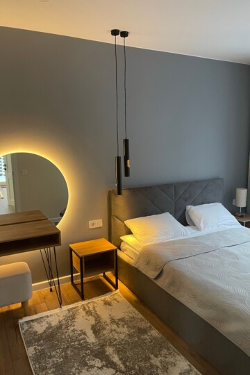 Sleep-friendly bedroom on a budget with white bedding, a gray upholstered headboard, and warm lighting.