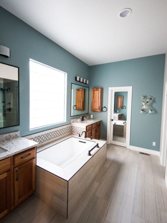 Whole home makeover inspiration featuring a bathroom with teal walls, wood vanities, a soaking tub, and a glass shower.