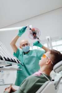 Dentist adjusting an exam light above a patient, illustrating a post about why dentists refer patients to specialists.
