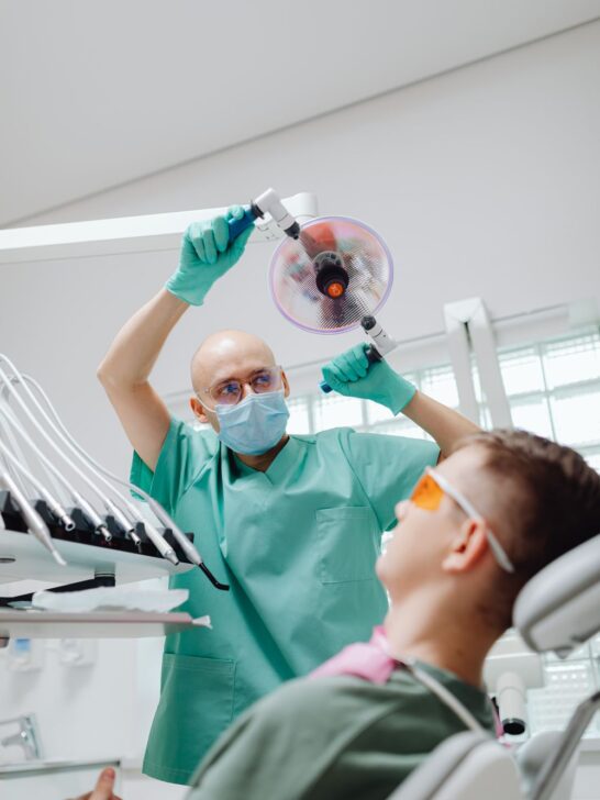 Dentist adjusting an exam light above a patient, illustrating a post about why dentists refer patients to specialists.